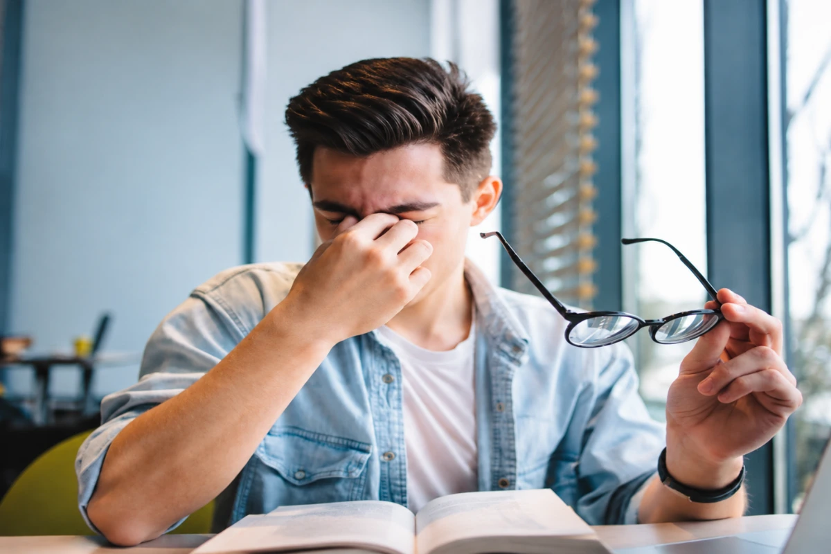 Man holding glasses and rubbing his eyes due to eye strain and digital fatigue caused by presbyopia